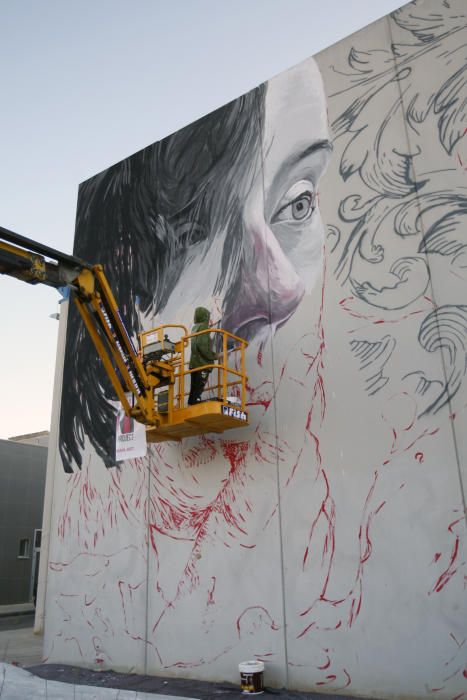 Lula Goce pinta un mural en la fachada de Bellas Artes de la UMU