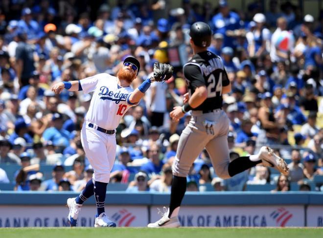 Justin Turner # 10 de los Dodgers de Los Angeles realiza una atrapada para terminar la tercera entrada frente a Ryan McMahon # 24 de los Colorado Rockies en el Dodger Stadium en Los Angeles, California.