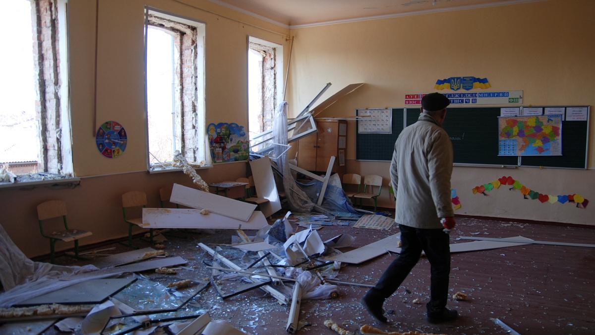 Un hombre camina entre los escombros de un colegio bombardeado por las tropas rusas.