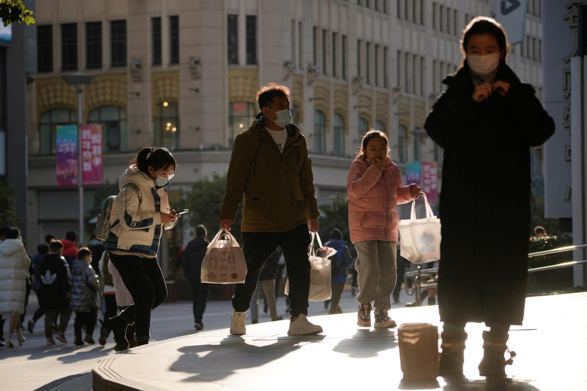 Las personas que usan máscaras protectoras caminan en un distrito comercial cuando China regresa al trabajo a pesar de los continuos brotes de la enfermedad por coronavirus (COVID-19) en Shanghái.