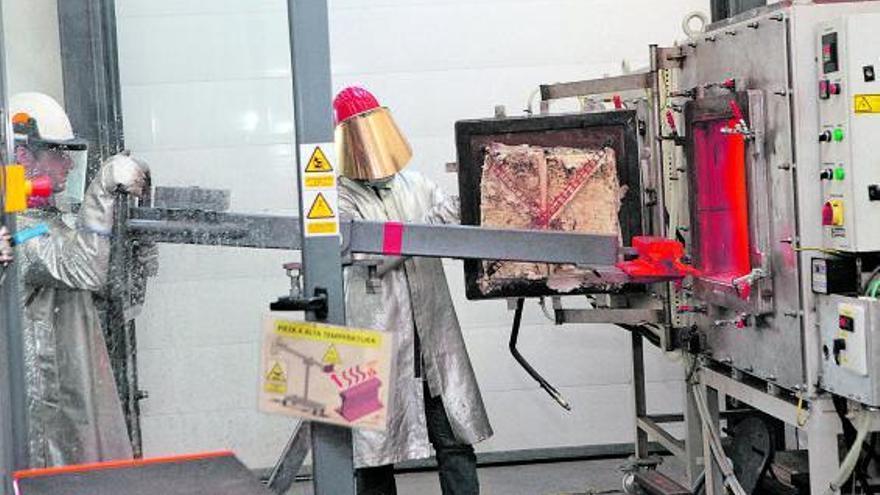 Dos investigadores de ArcelorMittal introducen un trozo de carril en un horno.
