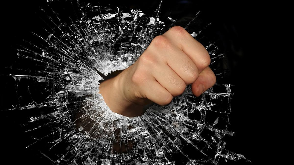 Una persona rompe un cristal con el puño