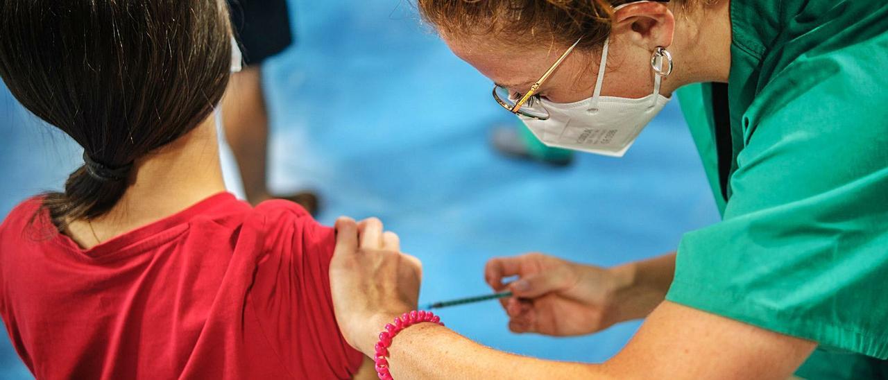 Una enfermera del Servicio Canario de la Salud vacuna a una joven en el vacunódromo del Pabellón Santiago Martín en Tenerife.