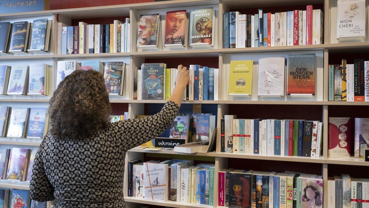 Eine Frau nimmt in der Buchhandlung „Bücher im Bogen“ einen Roman aus dem Verkaufsregal.