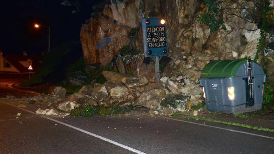 Arriba, estado en el que quedó la carretera y la acera tras el desprendimiento. Abajo, la Policía Local en A Guía.  // G.N.