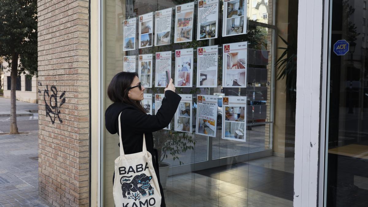 Una mujer fotografía uno de los anuncios de un escaparate de una agencia inmobiliaria. Los precios del alquiler siguen sin freno y en Castelló alcanzan un máximo histórico.