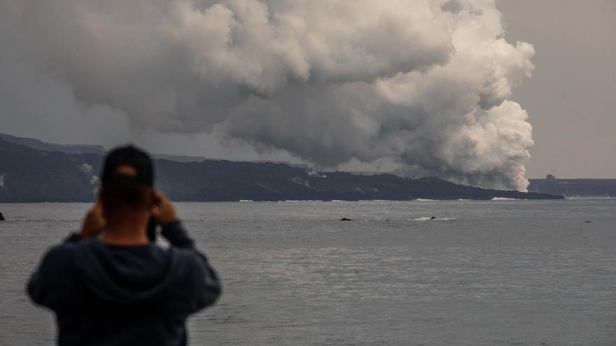 Una persona fotografía una columna de gases de la tercera colada que llega al mar desde el puerto Tazacorte