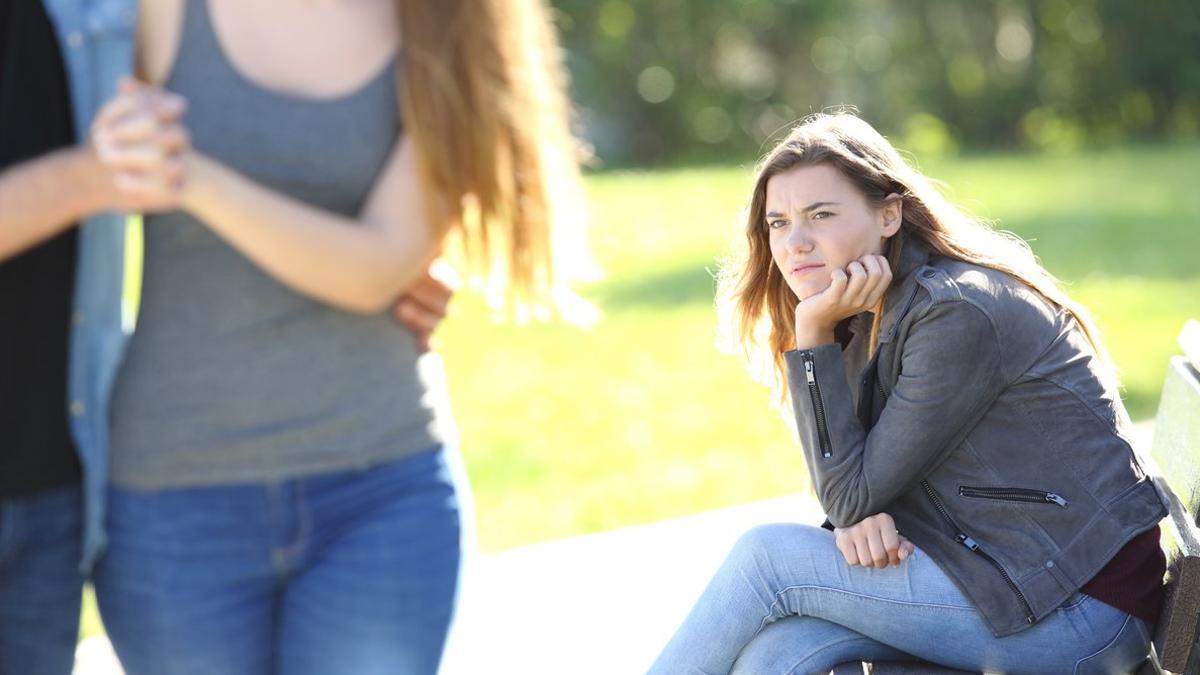 Chica sentada en el parque sintiendo envidia