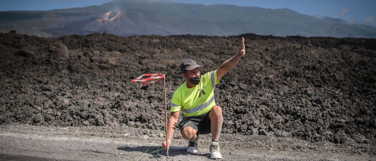 Un operario marcando el trazado de una carretera afectada por las coladas de lava procedentes de la erupción volcánica de La Palma . | | ANDRÉS GUTIÉRREZ