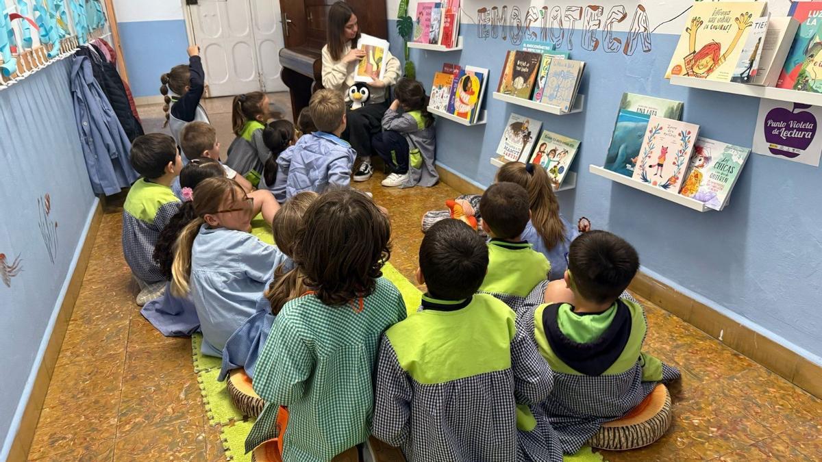 Los pequeños del centro, durante una actividad por el Día del Libro, con la profesora, al fondo, con un pinguino de peluche.