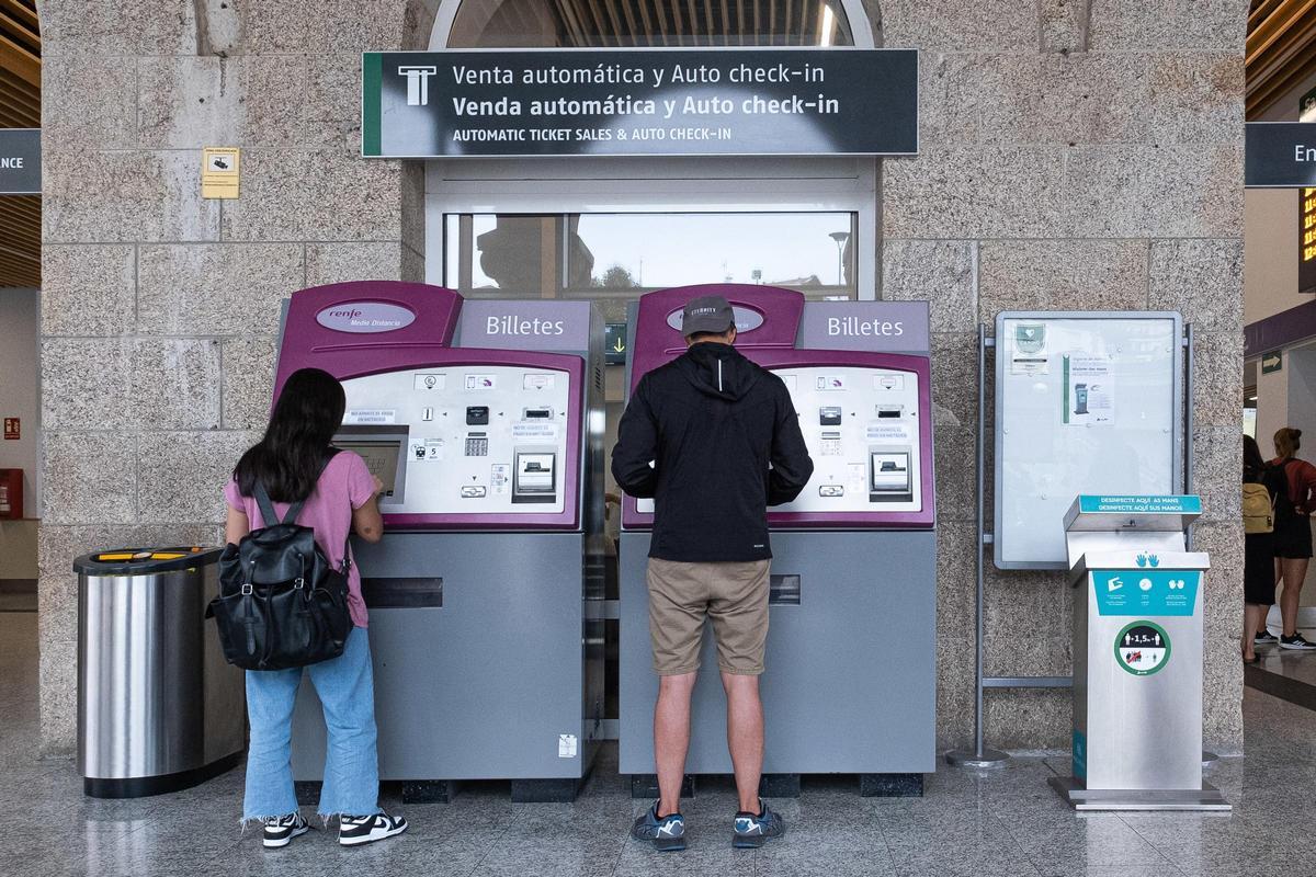 Dos personas compran billetes en los puestos de venta automática en Santiago