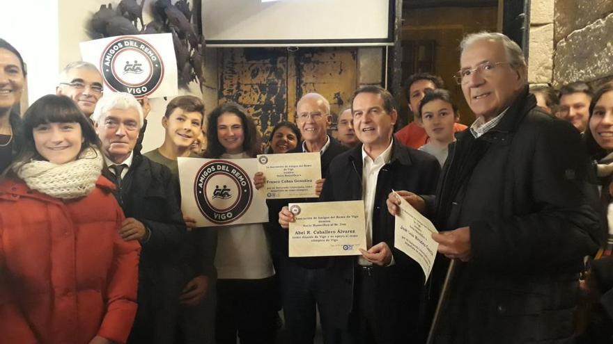 El alcalde entre Franco Cobas y José Luis Méndez, mostrando sus diplomas personales, a la izquierda Manel Fernández, concejal de Deportes, con el logo de la asociación, y Celia Cabrera asomando sobre el hombro de Cobas. Todos rodeados de deportistas, padres y familiares entusiastas miembros de la asociación.