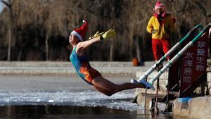 cmontanyes41411987 a woman wearing a santa hat dives into a partly frozen lake 171225123318