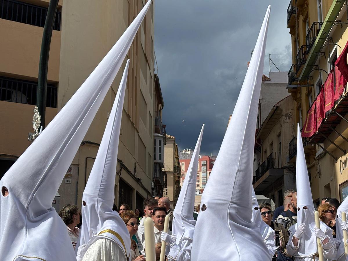 Las nubes negras en el horizonte no presagiaban nada bueno cuando los nazarenos del Rocío bajaban por Carretería.