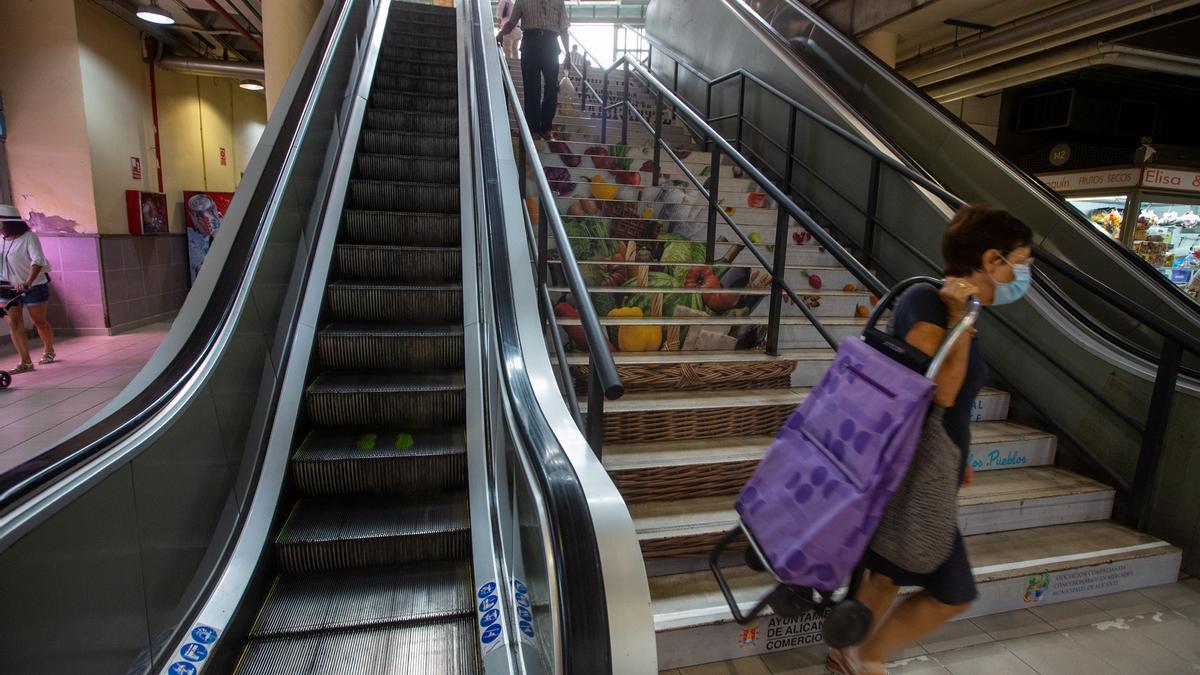 Una mujer carga con su carro al no funcionar las escaleras automáticas de bajada