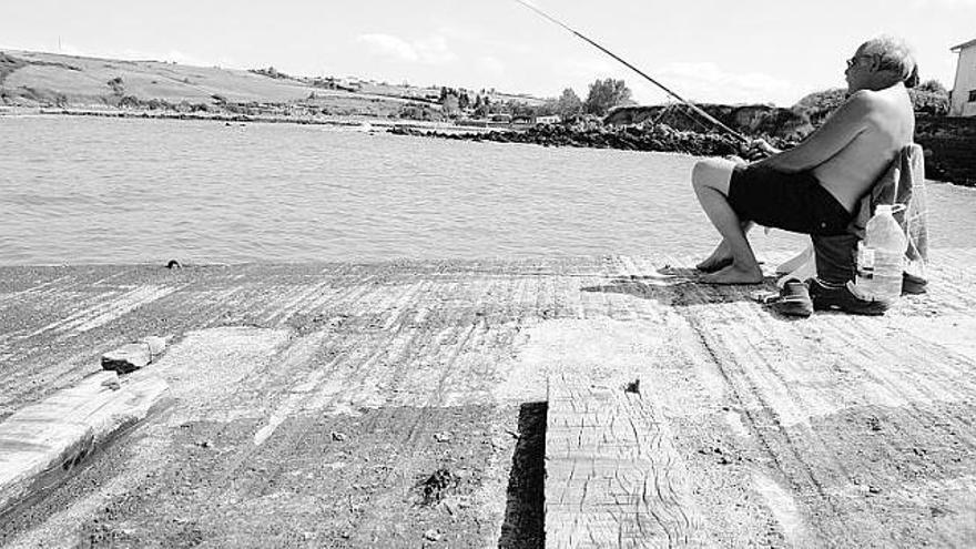 Un pescador en el puerto de Bañugues.