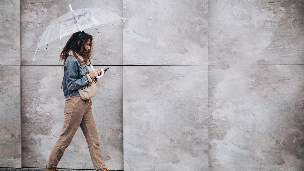 Una mujer pasea bajo la lluvia con un paraguas.