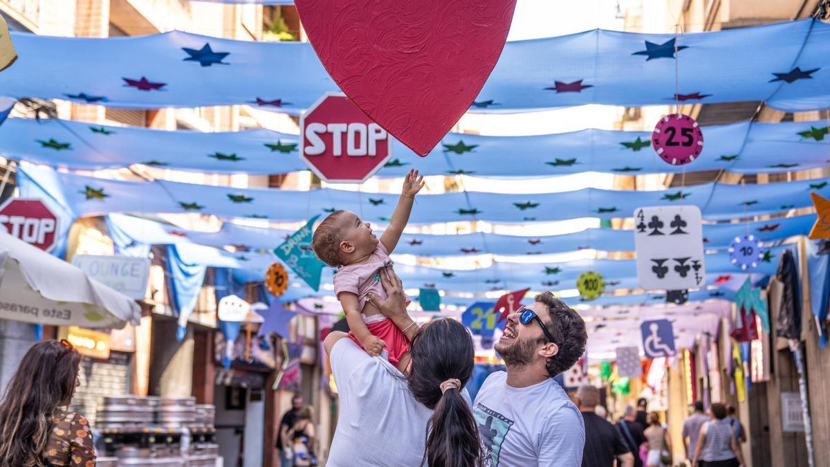 Una familia en la calle Providència, durante las fiestas de Gràcia 2024.