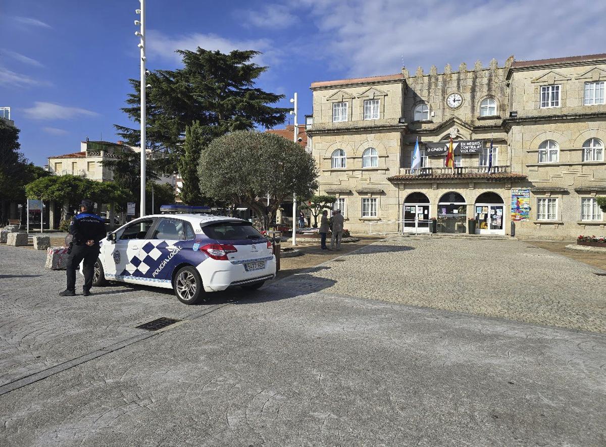 Un coche patrulla y un agente ante la casa consistorial grovense. | M. MÉNDEZ