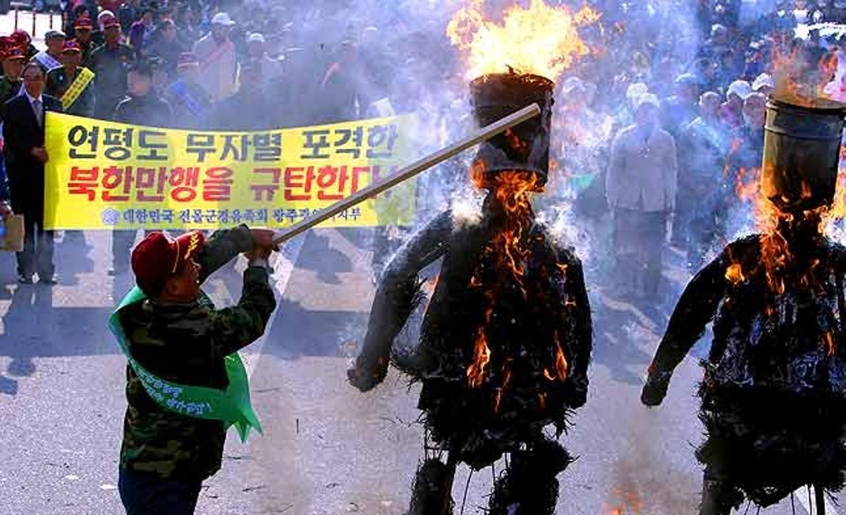 Un membre de l’Organització Coreana de Veterans Mutilats pega a dos ninots que representen el líder nord-coreà Kim Jong Il i el seu fill Kim Jong Un, durant una manifestació contra els bombardejos que Corea del Nord va portar a terme a l’illa de Yeonpyeong (Corea del Sud).