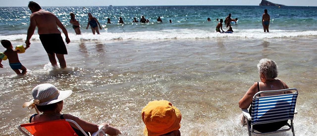 Tres turistas senior disfrutan del mar en la playa de Levante de Benidorm.