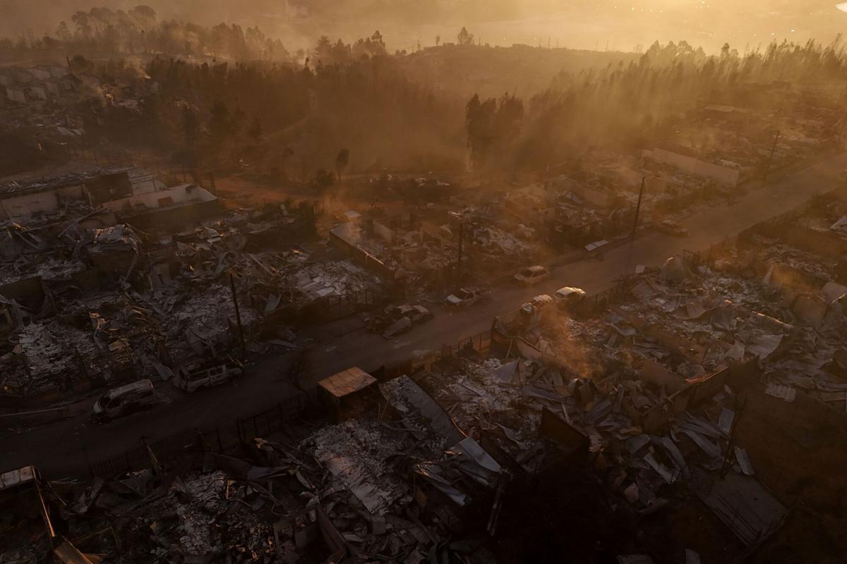 Vista aérea de los restos carbonizados de casas destruidas al atardecer después de un incendio forestal en Concepción, Chile, el 18 de enero de 2026.