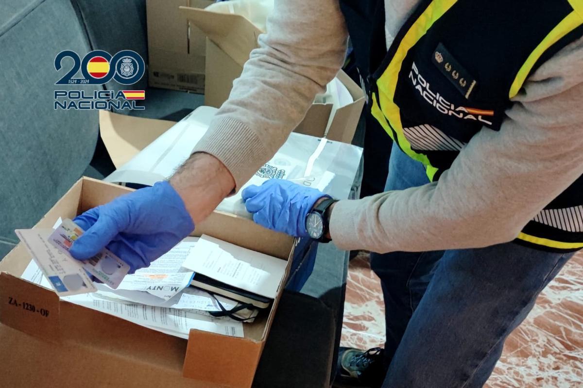 Un agente de la Policía Nacional requisando una serie de documentos falsificados