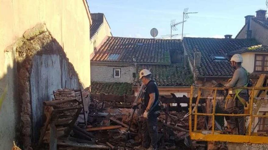 Los operarios derriban el tejado del edificio de la calle Doctor Cuesta Olay, en Noreña.