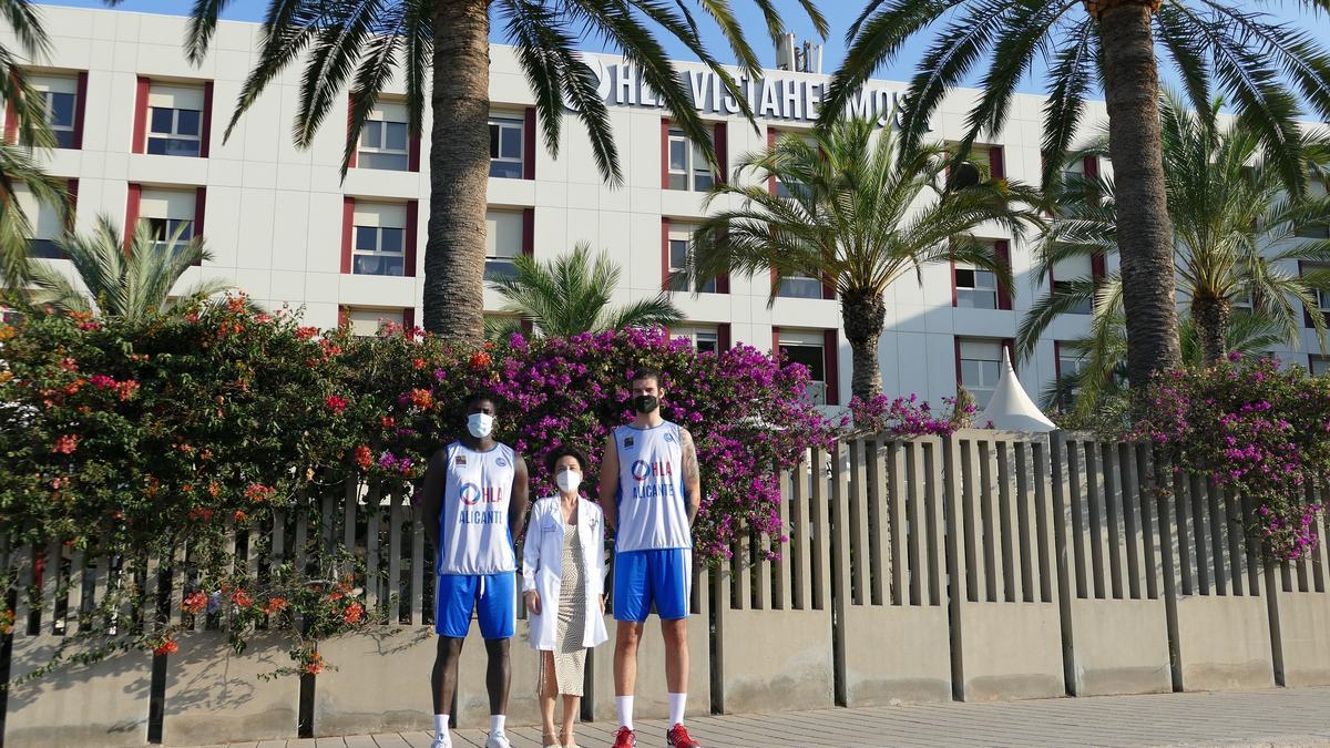 La directora médica de HLA Vistahermosa, Dra. Concha Giner, acompañada por los jugadores Walter Junior Cabral Bueriberi y Aaron Joseph Menzies del equipo HLA Alicante de baloncesto