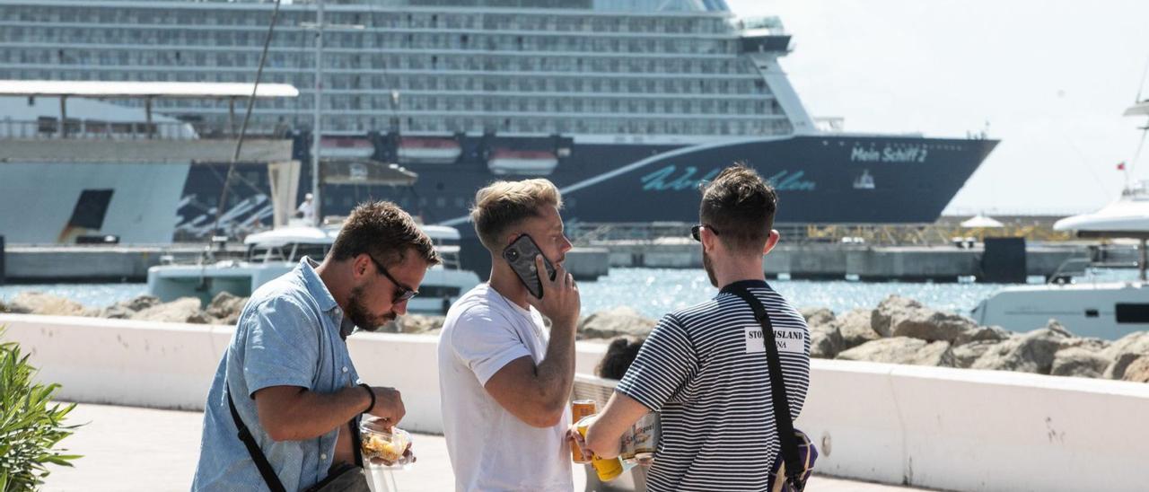 Tres turistas frente al crucero ‘Mein Schiff 2’ en una de sus escalas en Eivissa en 2021. | ZOWY VOETEN