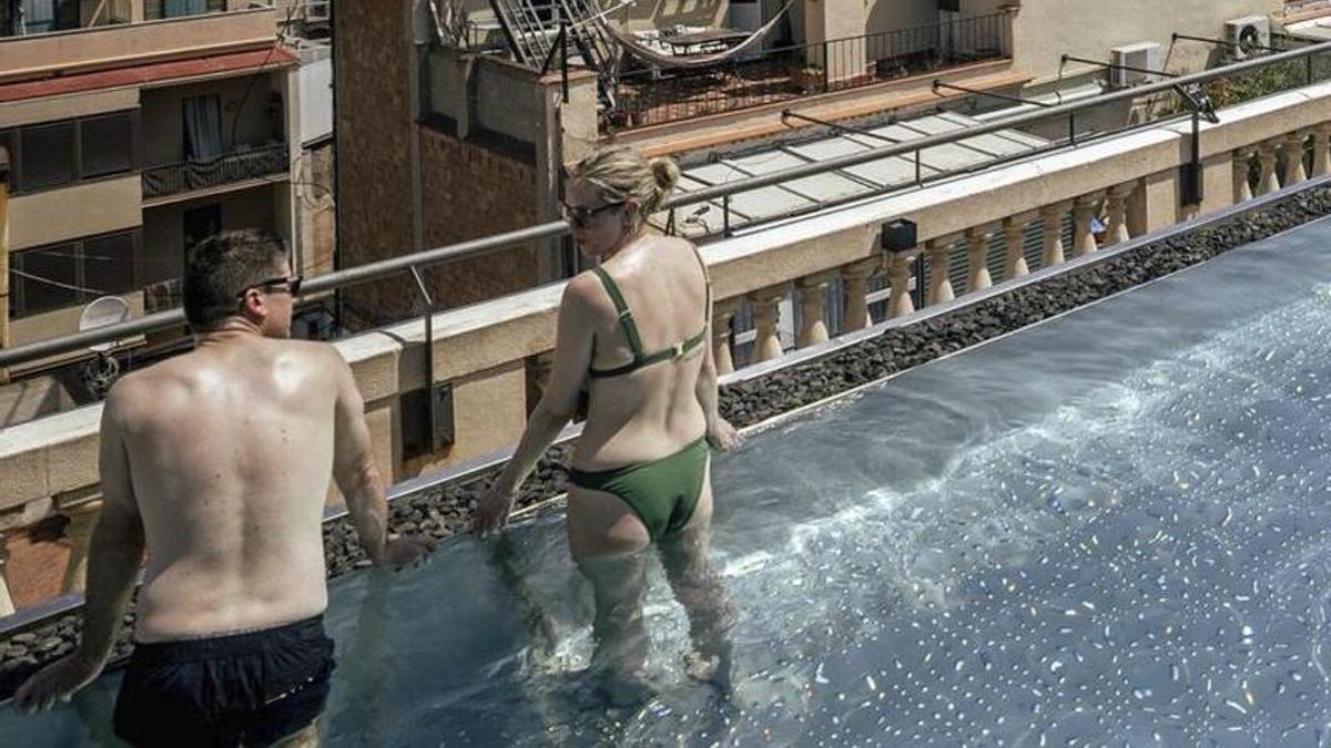 Dos turistes es refresquen a la piscina d’un hotel a Barcelona. | JORDI OTIX