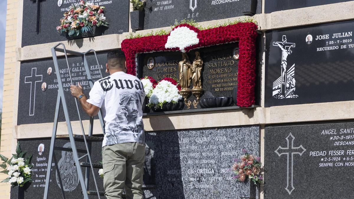 Un home posa flors en un nínxol del Cementeri General