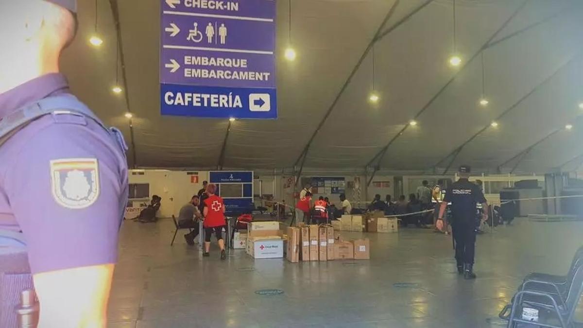 Voluntarios de Cruz Roja y Policía Nacional atienden a los migrantes recién llegados en la antigua estación marítima de Ibiza.