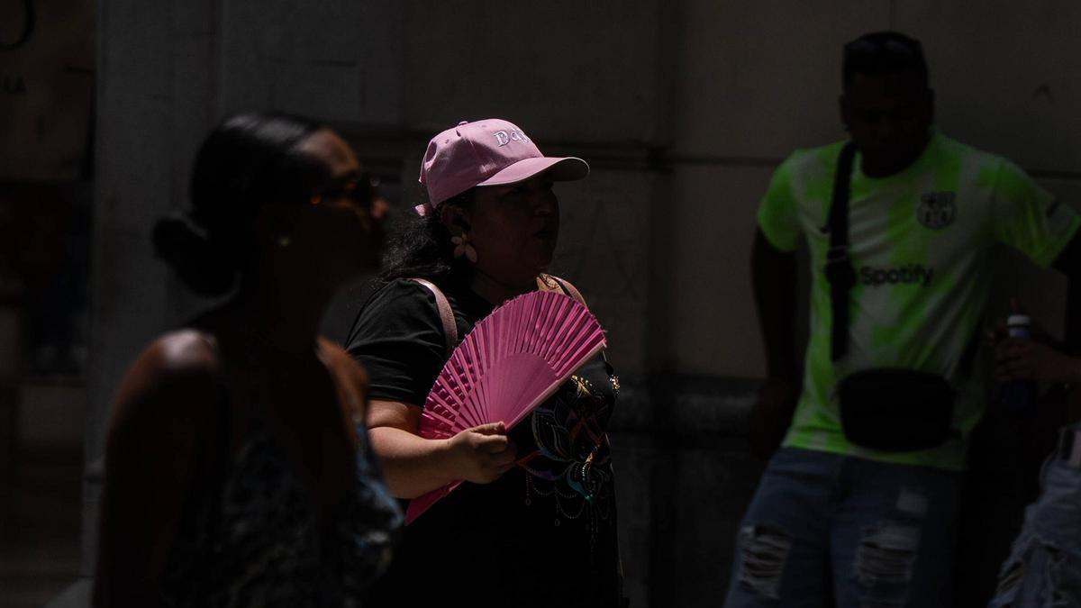 Una dona es venta mentre passeja pel carrer durant un dia de calor