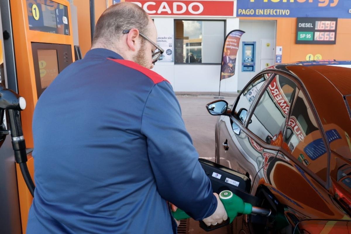 El empleado de una gasolinera de Cartagena usa la manguera para llenar el depósito de un coche.