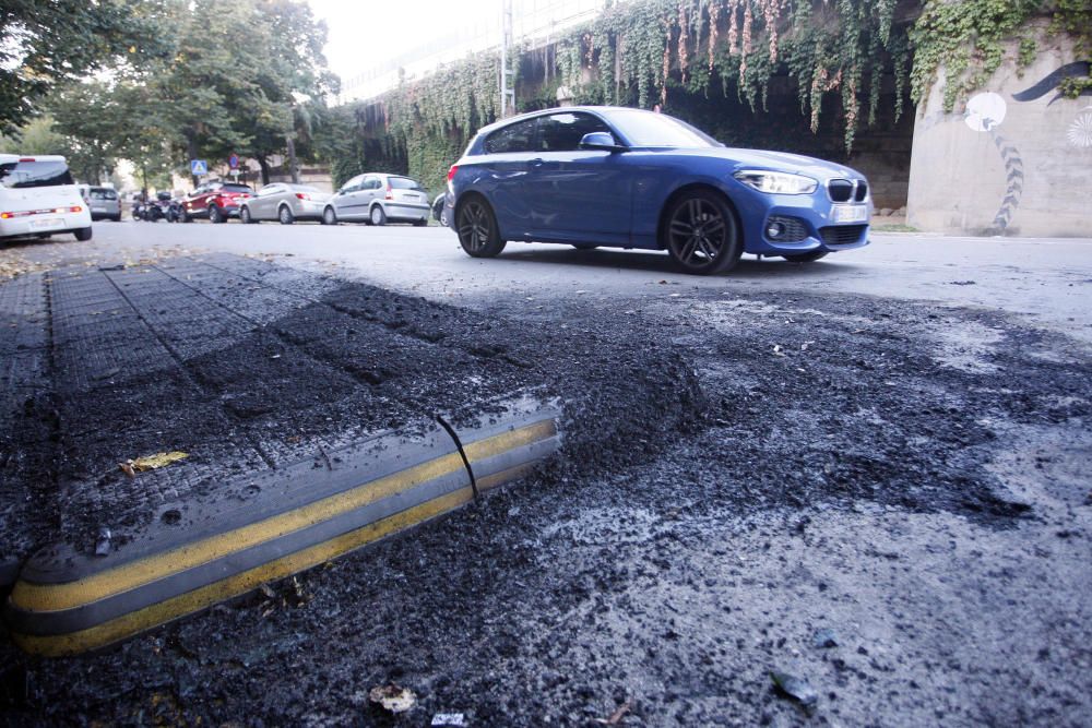 Carrers amb restes de mobiliari urbà cremat, contenidors per terra i treballadors de la brigada treballant