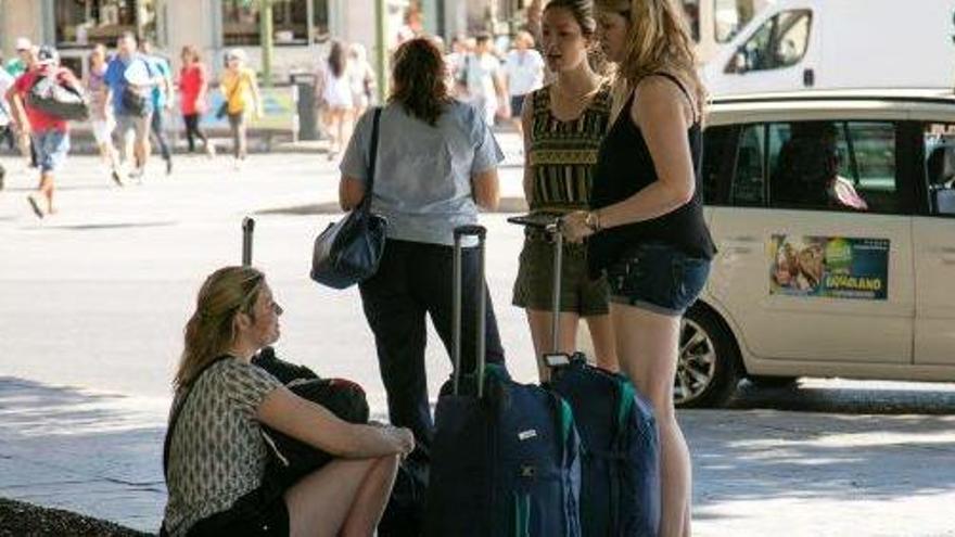 Imagen de turistas con sus maletas en el centro de Palma.