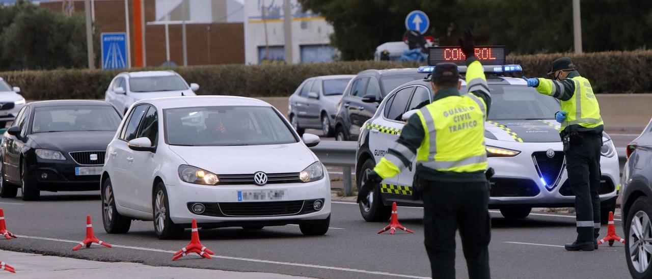 Dos guardias civiles ordenan parar a un vehículo en un control a la entrada de València.  | M.A. MONTESINOS