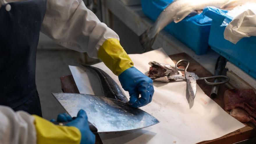 Una trabajadora atiende a una clienta en una pescadería. |