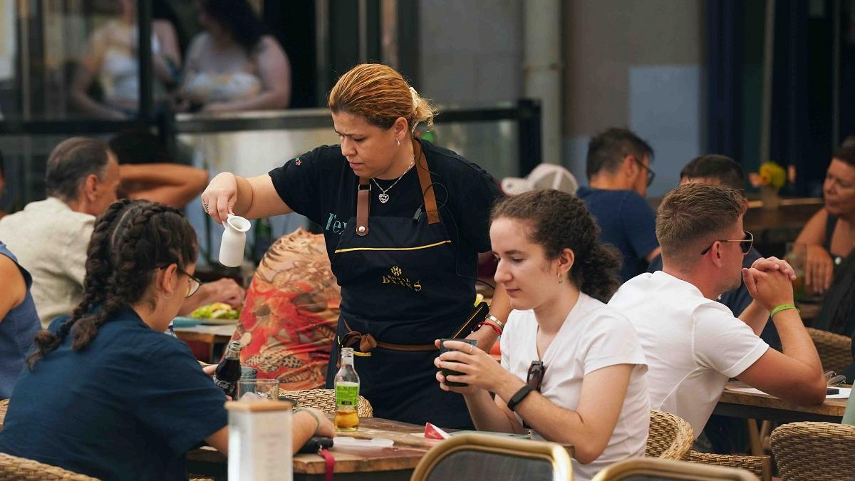 Una camarera atiende a sus clientes en un establacimiento de hostelería del Centro de Málaga.
