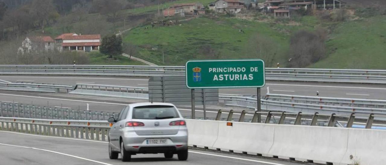 Un coche pasa ante el cartel de &quot;Principado de Asturias&quot; en Unquera, con Pimiango al fondo.