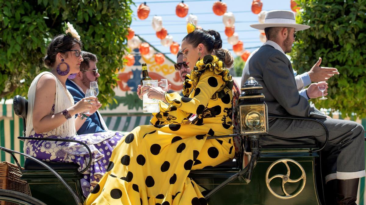 Unos amigos pasean en carruaje por el Real de la Feria de Abril de Sevilla.