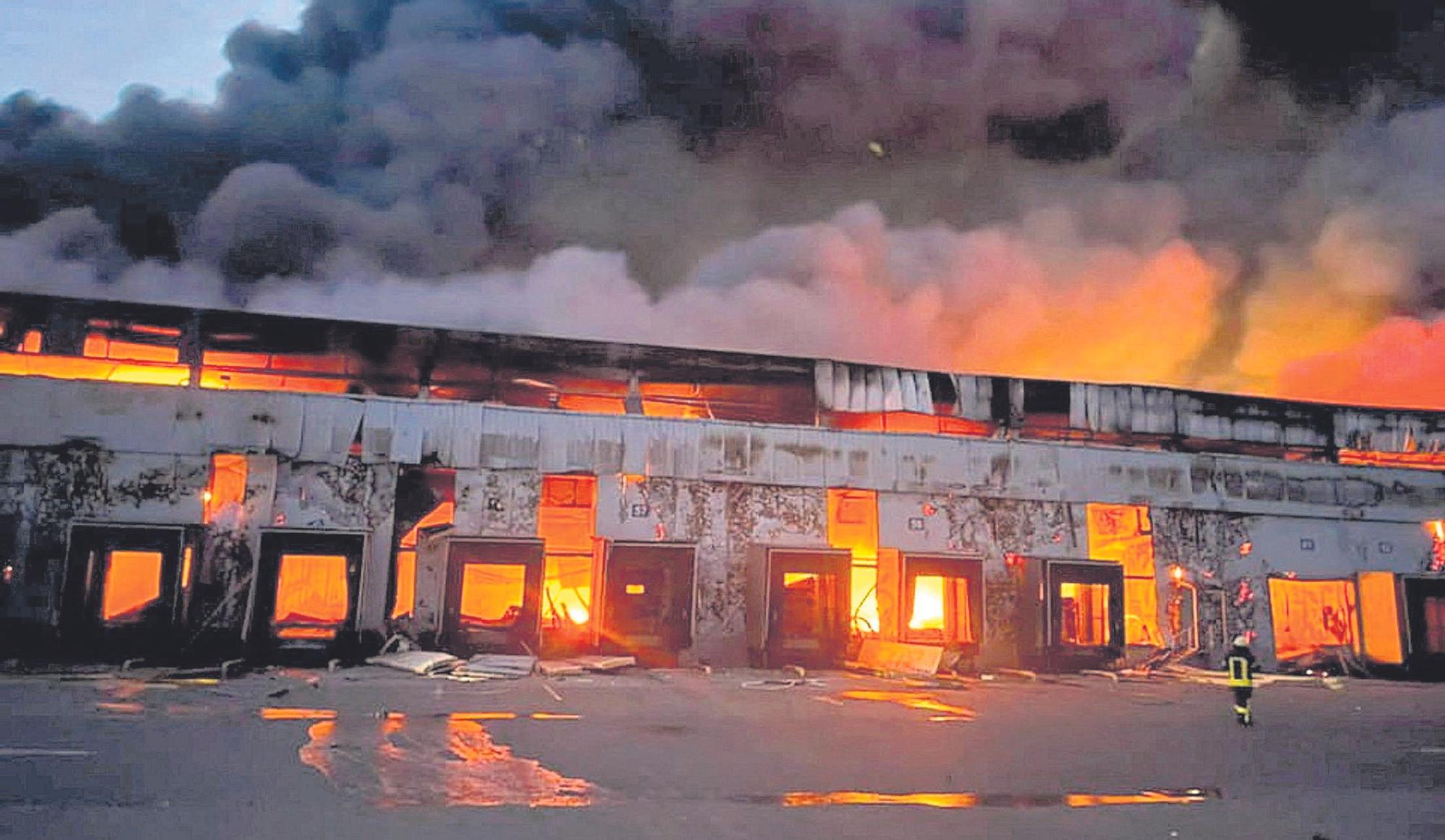 Un almacén de productos congelados se ve en llamas después de un bombardeo.