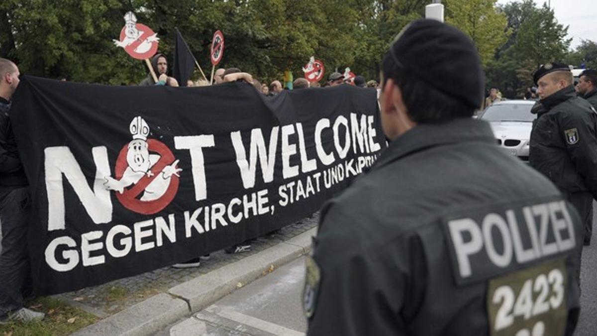 Policías miran a los manifestantes que cargan una pancarta contra la visita del Papa Benedicto XVI, ayer, en Berlín, Alemania.