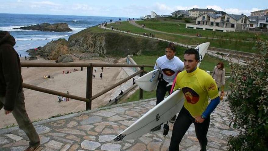 Dos surfistas recién salidos del agua, en la playa de Tapia.