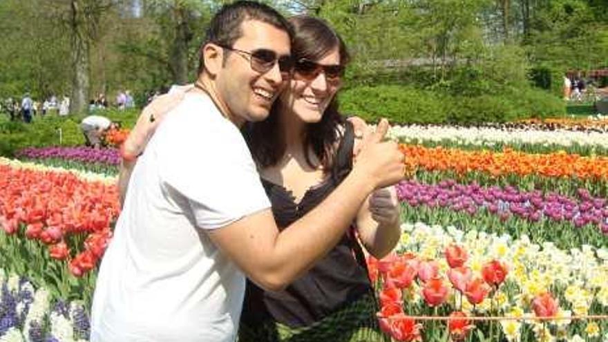 Alexia y su pareja posan frente a un paseo en Ámsterdam repleto de flores.