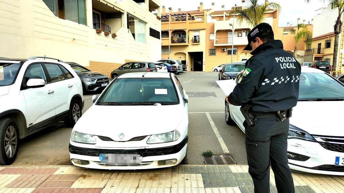 Un agente de la Policía Local toma nota de un vehículo abandonado en Rincón.