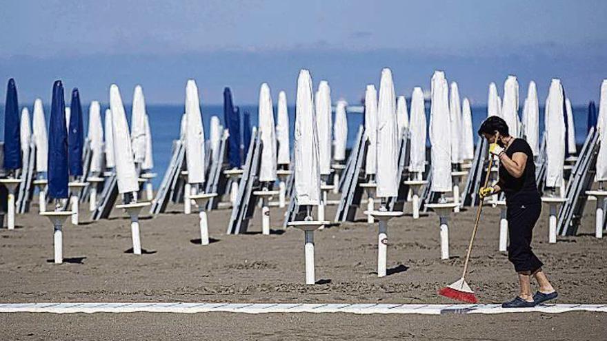 Una mujer limpia los accesos de una playa italiana. Epa/Massimo Percossi