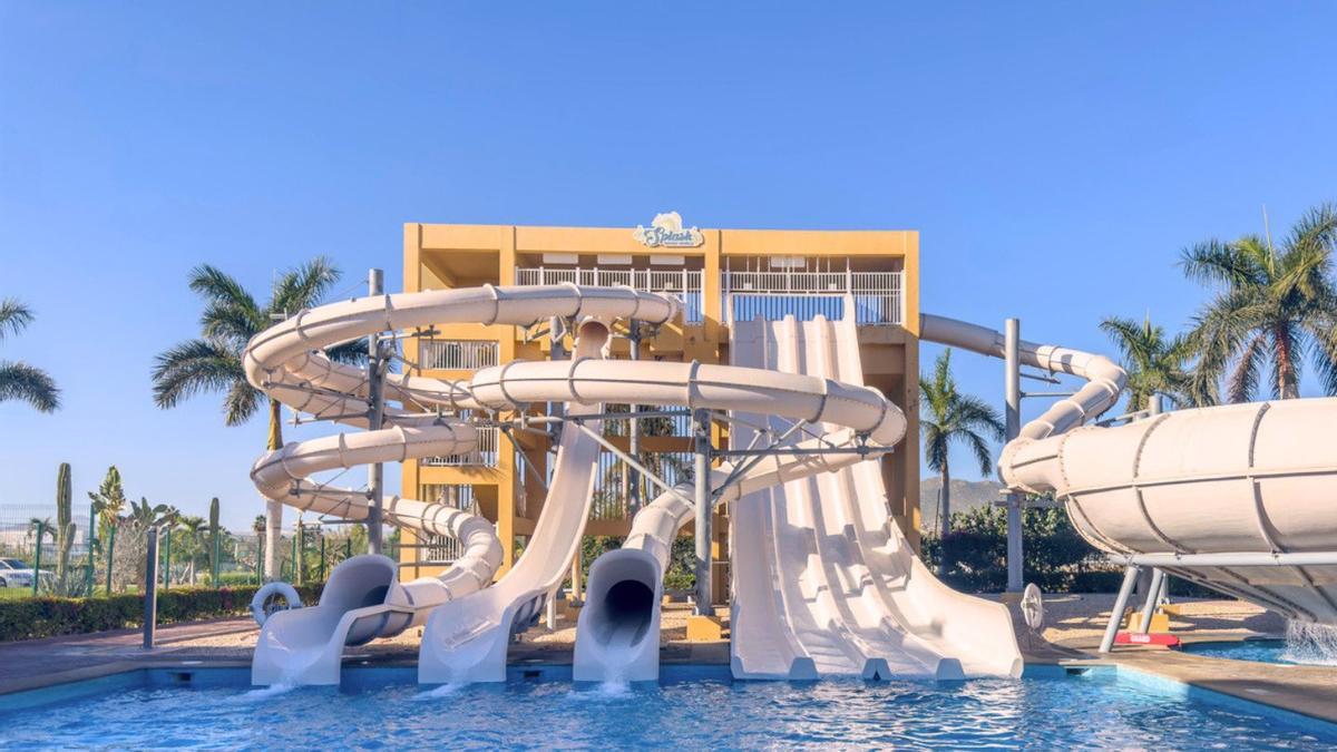 Un parque acuático de varios niveles con múltiples toboganes, algunos cerrados y otros abiertos, que conducen a una gran piscina