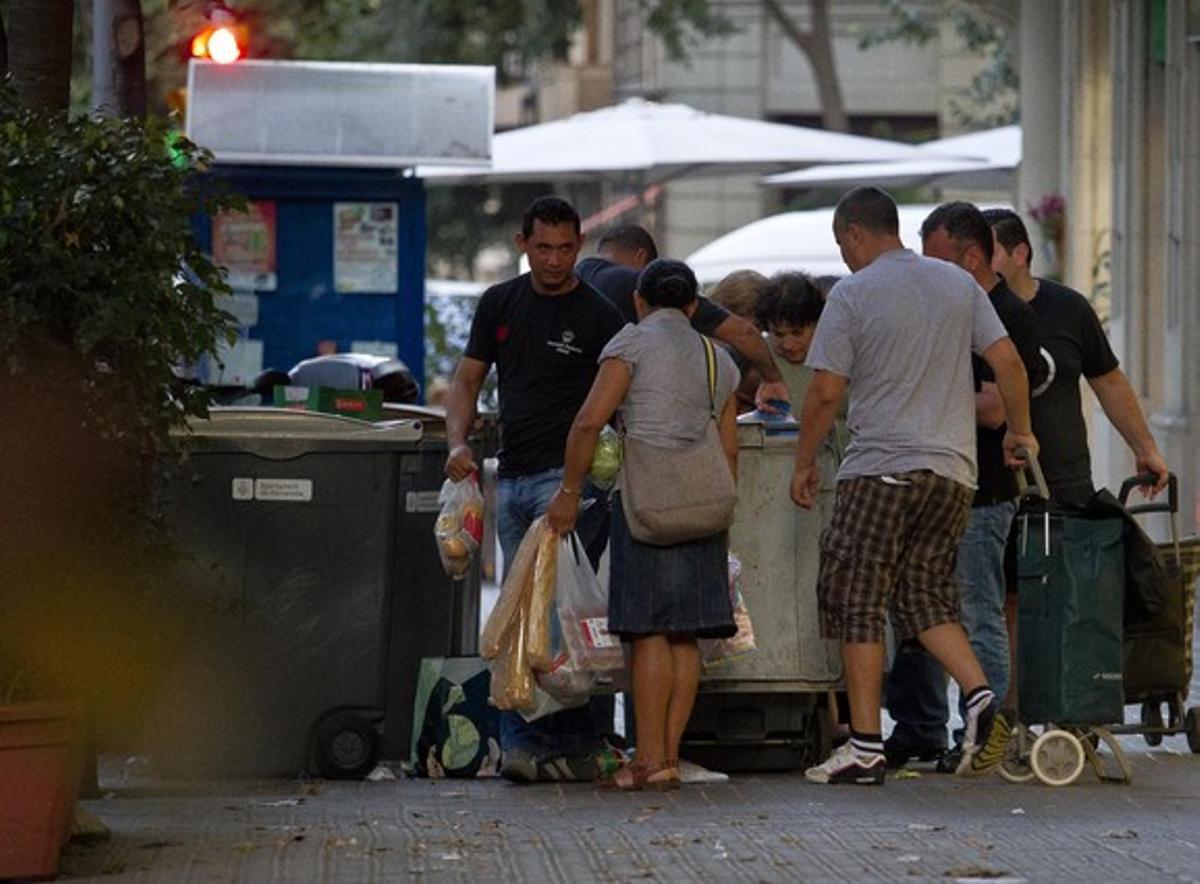Diverses persones agafen menjar caducat dels contenidors d’un supermercat, a Barcelona.
